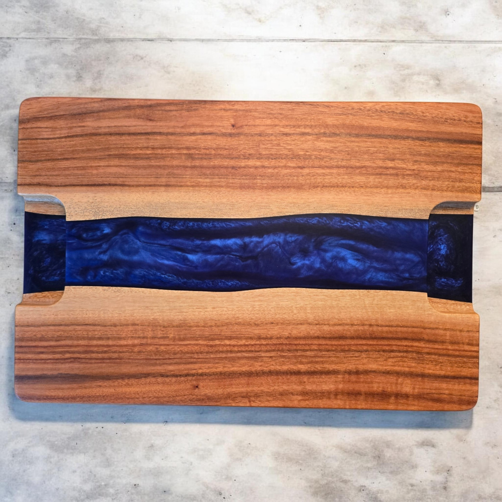 Underside of tigerwood and blue epoxy serving tray showing recessed routed handles