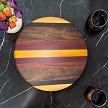 Striped hardwood lazy Susan on a black marble table with flowers and two glasses 